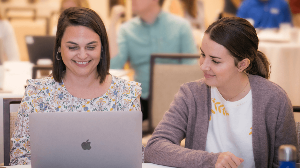 Two women working at a laptop screen